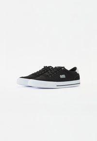 Mustad mustad sneakerid musta kummist tallaga, millel on valge varbasaapakas, mustad paelad ja logo külgedel. Sile tekstuur, madal disain.
