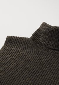 Ribbet genser med høy hals i mørk olivengrønn, med en tettsittende krage og teksturert stoff. Designet fremhever varme og komfort.
