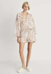 Loungewear set met bloemenprint in zachte pastelroze, met een knoopsluiting top met brede mouwen en bijpassende shorts, gemaakt van lichtgewicht materiaal.