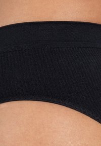 Culotte noire côtelée avec une taille élastique douce. Le tissu a une texture lisse et une finition propre le long des bords.