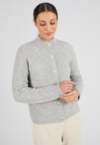 Cárdigan de punto en gris con un alto cuello, que presenta grandes botones en color crema y puños de manga acanalados. Tejido texturizado, diseño ajustado.