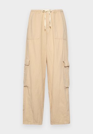 Beige cargo pants with an elastic waistband and drawstring, featuring two large side pockets and a loose, relaxed fit.