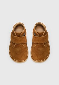 Zapatos de ante marrón para toddlers con punta redondeada, correa de velcro y costuras blancas, que presentan un diseño sencillo y una textura suave.