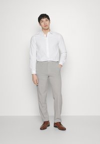 White button-up shirt, light gray trousers, brown shoes. Slim fit with long sleeves and smooth texture, minimalistic design, no patterns.