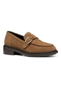 Mocasines de ante marrón con punta redondeada, hebilla decorativa prominente y suela de goma texturizada. El diseño presenta acentos de costura.