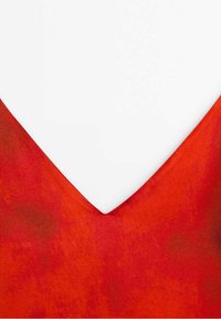 Röd v-ringad plagg med ett slätt, lätt texturerat tyg. Urringningen har ett skarpt, djupt snitt. Färgen har en subtil tonvariation.