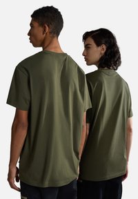 Camisetas de algodón de corte relajado en color verde oliva, de manga corta, cuello redondo, con dobladillo recto y un diseño minimalista.