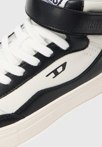 Fekete-fehér Diesel magas szárú sneaker fehér fűzőkkel, oldalpaneljén logóval és bokakörüli pánttal.