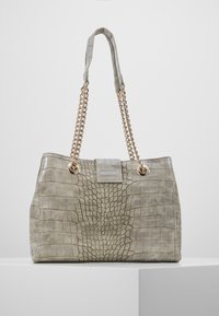 Grå krokodilmönstrad konstläderhandväska med guldkedjeaccent, som har ett handtag upptill och en luckstängning fram.