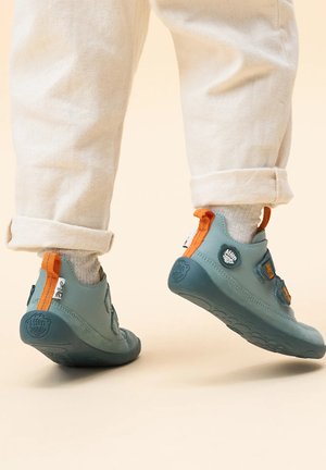 Blau-graue flexible Schuhe mit orangefarbenen Akzenten, ausgestattet mit Klettverschlussriemen, runder Zehenform und strukturierten Gummisohlen.