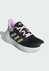 Chaussure de sport noire avec des accents roses et une semelle blanche. Comprend une tige en mesh et trois rayures de couleurs vertes, roses et vert clair.