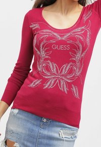 Maglione fucsia a maniche lunghe con scollo rotondo e decorazioni in cristallo con logo del brand al centro.