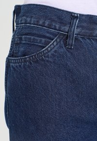 Mörka denimjeans med en slät textur, med en klassisk femficksdesign, ton-i-ton sömmar och en rak skärning vid midjan.