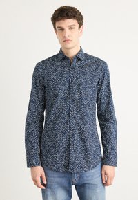 Navy blue button-up shirt with a floral white print, long sleeves, and a classic collar, made from a soft, textured fabric.
