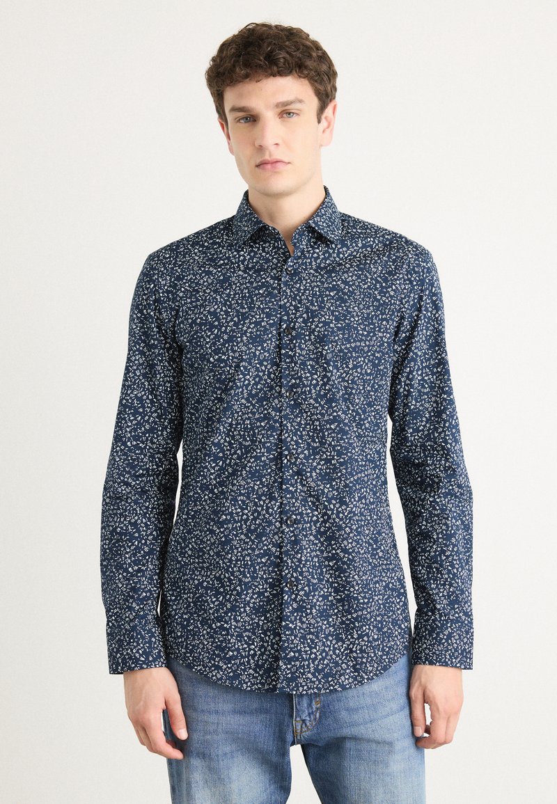 Navy blue button-up shirt with a floral white print, long sleeves, and a classic collar, made from a soft, textured fabric.