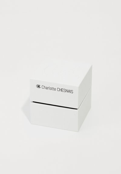 Weißer quadratischer Karton mit glatter Oberfläche, mit geprägten Mustern und dem Text "Charlotte CHESNAIS" in Schwarz auf der Vorderseite.