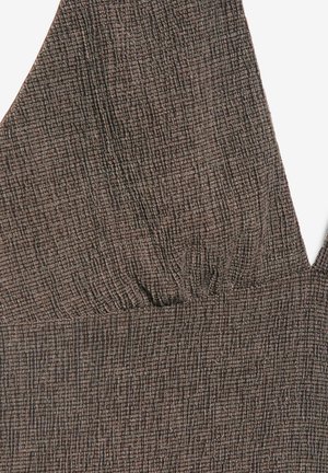 Nærbillede af brunt stof med et tekstureret gittermønster og en V-udskæring med subtile rynker ved brystområdet.
