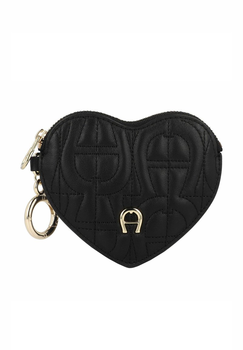 Bolso de cuero negro en forma de corazón con textura acolchada, equipado con accesorios dorados y un llavero. Detalle de logo en relieve en el frente.