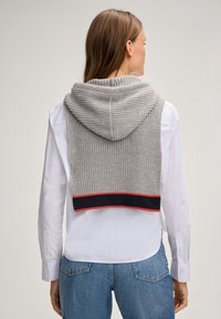 Grau gestrickter Hoodie-Pullover mit Rippenmuster und einem Saum mit roten und marineblauen Streifen. Wird über einem weißen Hemd mit Kragen getragen. Einfacher, strukturierter Stil.