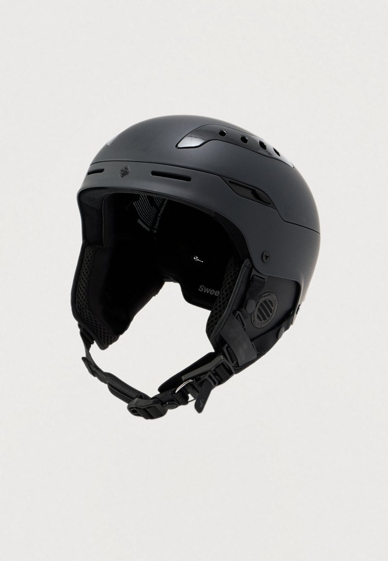 Zwarte sk helmet met een gladde schaal, meerdere ventilatiegaten, gevoerde binnenkant, verstelbare riem en kenmerkend logodetail.