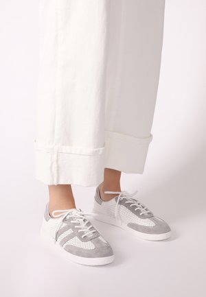 Athletic shoes in gray and white, featuring perforated panels, suede texture, and a soft rubber sole. Laces are white and threaded through eyelets.