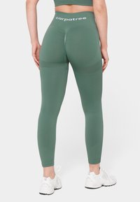 Roheline aktiivne leggingud on sileda tekstuuriga, kõrge vöökohaga, millel on "carpatree" logo, ning kontrastsete võrkpaneelidega reites.