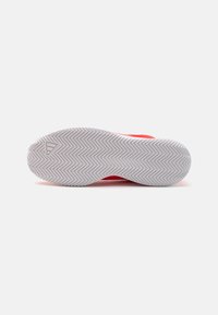 Adidaș roșu de sport cu un superior texturat, având o talpă de cauciuc albă cu un model în zigzag pentru aderență. Fără detalii vizibile de branding.