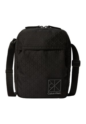 Petit sac bandoulière noir Calvin Klein avec sangle réglable et motif logo discret embossé sur le tissu.