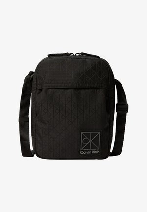 Petit sac bandoulière noir Calvin Klein avec sangle réglable et motif logo discret embossé sur le tissu.