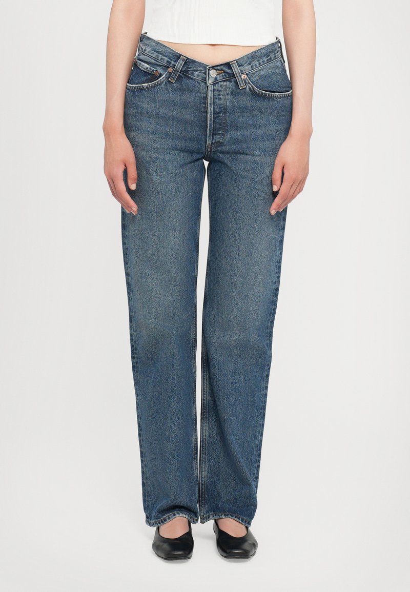 Jean en denim bleu avec une coupe droite, taille haute et un léger délavage. Présente un style classique à cinq poches et des finitions en métal.