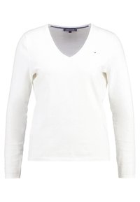 Valkoinen pitkähihainen v-kaula-aukkoinen pusero pehmeästä kankaasta. Varustettu resorireunuksilla helmassa ja hihoissa sekä pienellä logolla rinnassa.