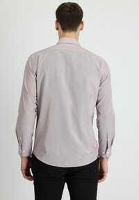 Lichtroze shirt met lange mouwen en een subtiel verticaal streeppatroon, met knoopsluiting aan de manchetten en een ronde onderrand. Gemaakt van een zachte stof.