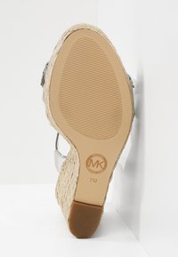 Semelle d'une sandale compensée beige avec côtés tissés, adhérence texturée, logo de la marque et taille 7M visible.