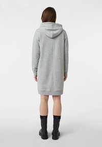 Szara sukienka dresowa z kapturem, długimi rękawami i ściągaczami przy mankietach. Charakteryzuje się prostym krojem i długością do kolan, zestawiona z czarnymi botkami za kostkę.