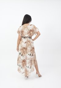 Floral maxi Kleid aus weichem Stoff in hellbraunen und grünen Farbtönen. Verfügt über fließende Ärmel, eine taillierte Taille und einen geschichteten Saum. Transparente Absätze.