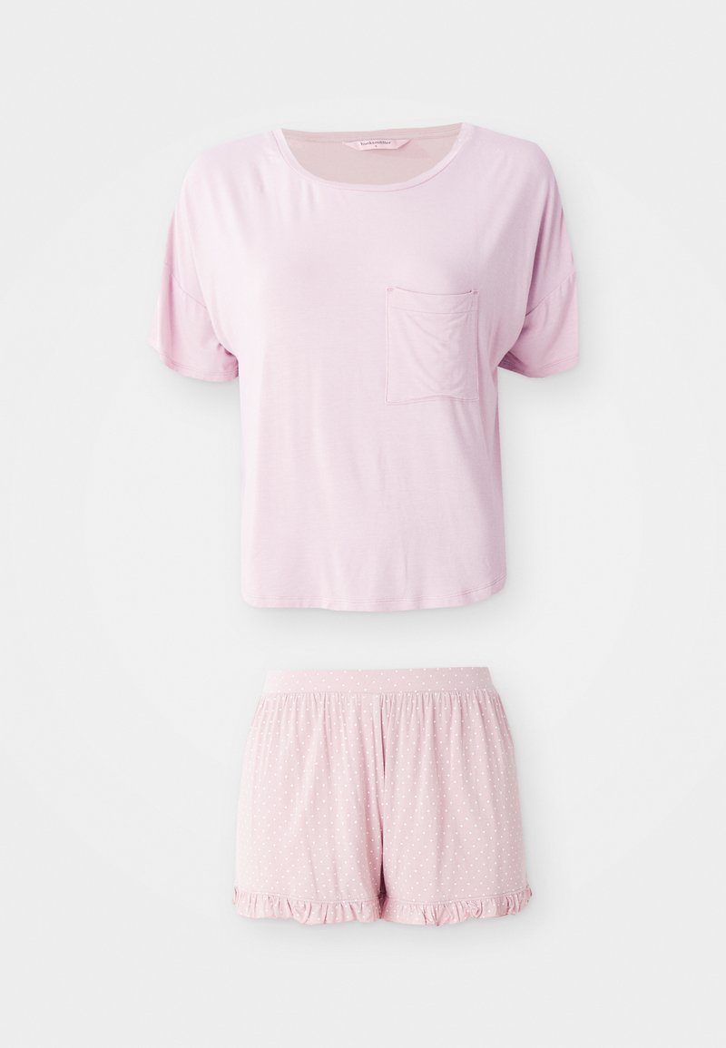 Ljusrosa pyjamasset med kort ärm som har en ficka på toppen och shorts med prickmönster och volangkant. Mjuk material.
