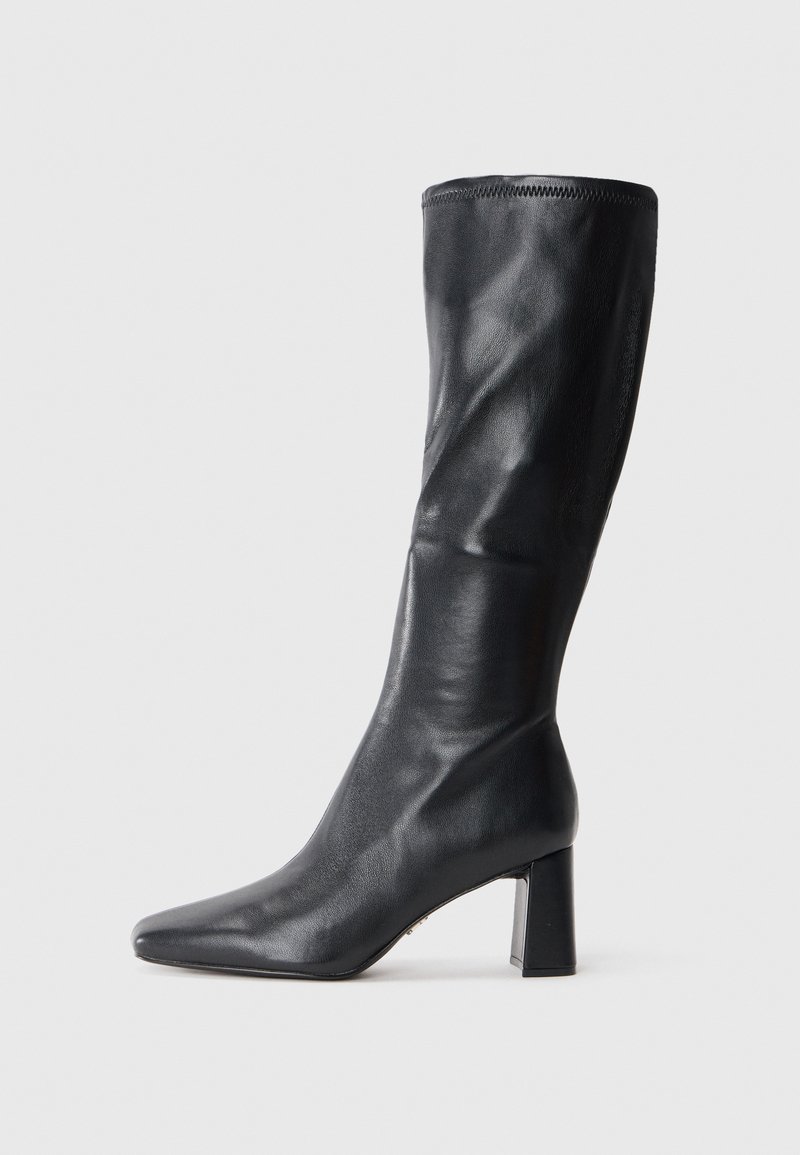 Stivale in pelle nera al ginocchio con punta affusolata e tacco largo. Texture liscia con un design elegante e dettagli di cucitura sottili.