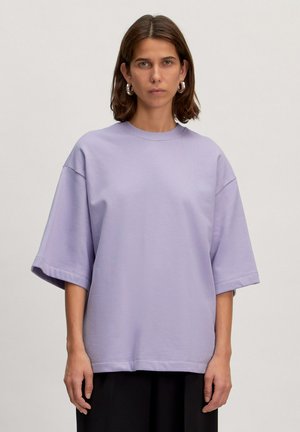 Lichtpaarse oversized t-shirt met korte mouwen, een ronde halslijn en een gladde textuur. Het item heeft een ontspannen pasvorm en minimale stikseldetails.