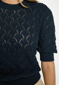 Navy blue knitted sweater featuring a textured, open lace pattern, short puff sleeves, and a ribbed neckline and hem.