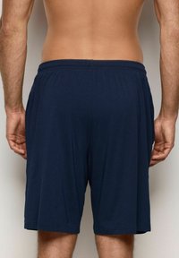 Námořnické modré sportovní šortky s elastickým pasem, vyrobené z měkkého materiálu, po kolena, se bočními kapsami a hladkým povrchem.