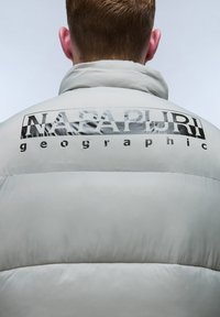 Ljusgrå puffjacka med hög krage, kviltad textur och stor svart "Napapijri geographic"-logotyp på övre delen av ryggen.
