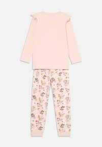 Ljust rosa långärmad topp med volangärmar, kombinerad med krämfärgade byxor med ett blommönster i rosa, lila och brunt.