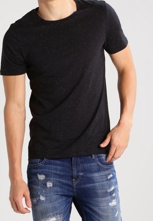 Schwarzes T-Shirt mit kurzen Ärmeln, dezenten Sprenkeln, rundem Ausschnitt und weicher Textur, kombiniert mit abgenutzten blauen Denim-Jeans.