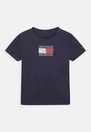 Navy toddler short-sleeve t-shirt with button on shoulder, featuring central rectangular Tommy Hilfiger logo in navy, white, and red colors.