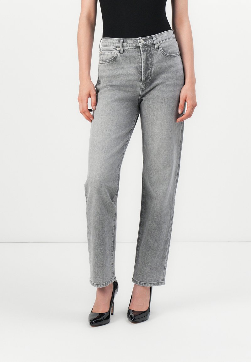 Lichtgrijze high-waisted jeans met een iets relaxte pasvorm. Gemaakt van denim, met voorzakken en een subtiele textuur. Gecombineerd met zwarte hakken.