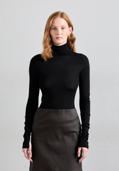 Schwarzer Rollkragenpullover mit langen Ärmeln, glatter Textur. Kombiniert mit einem dunkelgrauen Bleistiftrock, der ein elegantes, minimalistisches Design aufweist.