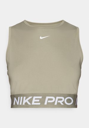 Sportowy stanik Nike Pro w oliwkowym kolorze, dopasowany krój, okrągły dekolt oraz biała logo na klatce piersiowej. Posiada szeroką elastyczną taśmę z nazwą marki.