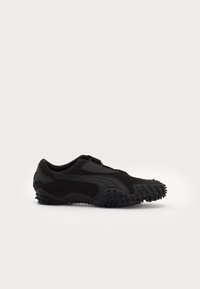 Zapatillas deportivas negras hechas de tela y goma, con una suela texturizada con picos para agarre y un diseño elegante y aerodinámico.