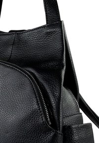 Sac à dos en cuir noir texturé avec une poche zippée à l'avant et deux bretelles, présenté sur fond blanc.