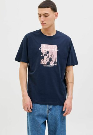 Mørkeblå bomulds T-shirt med en kaktusgrafik i pink, der har rund hals og korte ærmer, parret med lyseblå denim jeans.